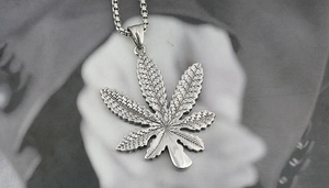 Macro shot of retro stainless steel maple leaf pendant with textured veins on square link chain