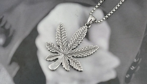 Macro shot of retro silver maple leaf pendant with detailed textures and box chain