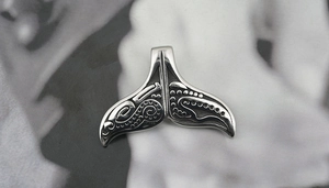Detailed view of a vintage silver whale tail pendant with tribal style engravings