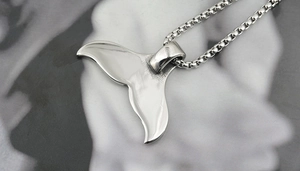 Detailed view of a polished stainless steel whale tail pendant with a classic box chain
