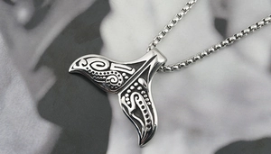 Detailed view of the whale tail pendant with tribal patterns on a steel box chain