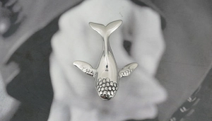 Macro shot of silver whale pendant showing detailed head texture and smooth fins
