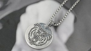 Macro shot of silver viking bear head pendant with intricate engraving and thick box chain