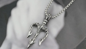Détail d'un pendentif trident en argent vintage avec des motifs baroques et une chaîne robuste