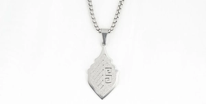Close-up of matte silver shield pendant with geometric engraving and box chain necklace