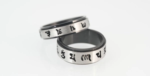 Macro shot of rotatable stainless steel spinner rings featuring black religious mantra engraving