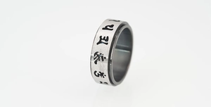 Macro detail of rotating stainless steel spinner ring with engraved Tibetan symbols