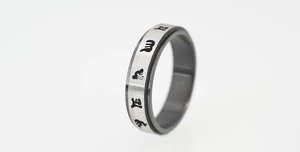 Macro view of rotating spinner ring with etched religious mantra on brushed steel