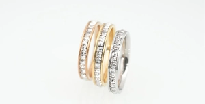 Detailed view of three stackable eternity rings in rose gold, gold, and silver finishes