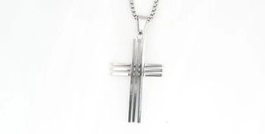 Detailed close-up of a silver cross pendant with industrial layered design on box chain