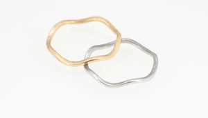 Makroaufnahme minimalistischer gewellter Titanstahlringe in Mattgold und Silber
