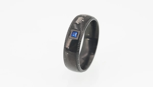 Vue détaillée d'une bague en acier titane noir avec pierre carrée bleue et gravure couronne