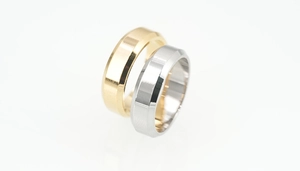 Detail of gold and silver titanium rings featuring polished beveled edges on a white background