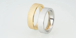 Close-up of minimalist gold and silver matte brushed titanium steel rings for couples