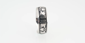 Detailed close-up of a silver steel band ring featuring a black enamel Claddagh design