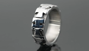 Close-up of titanium steel ring featuring hollow iron cross patterns and oxidized finish