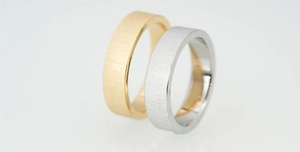 Macro detail of gold and silver couple rings showing vertical brushed texture and polished inner band