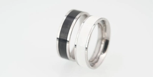 Macro shot of black and white enamel couple rings with polished stainless steel edges