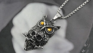 Detailed close-up of retro silver owl pendant with skull motif and yellow gemstone eyes