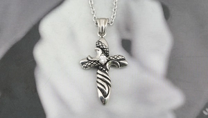 Macro shot of gothic titanium steel cross pendant with diamond and snake scale texture