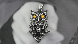Detail of vintage owl skull pendant with yellow zircon eyes and aged steel texture