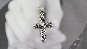 Macro shot of gothic silver cross pendant with central sparkling zircon stone