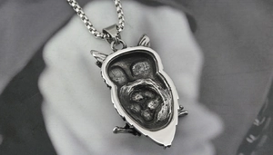 Detailed view of owl pendant showing the hollow-out back texture and steel box chain link