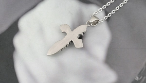 Close-up of silver cross sword pendant featuring brushed metal and gothic engraving