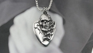 Macro view of gothic skull relief on guitar pick pendant with retro box chain