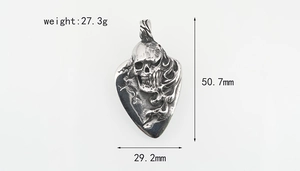 Detailed macro view showing a gothic skull guitar pick pendant with flame engraving