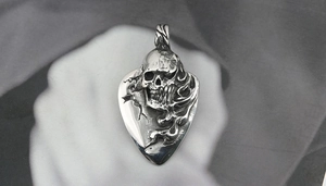 Macro shot of vintage skull pendant in guitar pick shape with rock style engraving