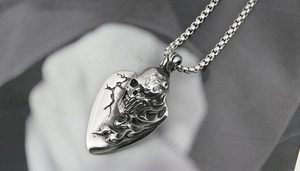 Detailed close-up of a gothic skull heart pendant with vintage oxidized steel finish
