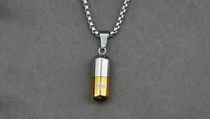 Vue macro d'un collier capsule bicolore avec gravure Be Mood et symbole de la croix