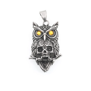 Vintage steel owl pendant with skull detail and amber-colored eyes on white background