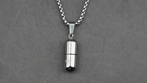 Détail du collier pendentif capsule De Mood avec design ouvrant et croix gravée sur métal
