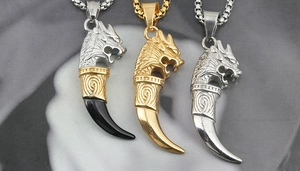 Detailed close-up of three dragon head tooth pendants in gold, silver and black-silver tones