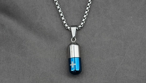 Détail d'un pendentif capsule en acier titane avec partie bleue et gravure Be Mood