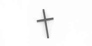 Gros plan d'un pendentif croix noire minimaliste avec finition métallique sur fond blanc