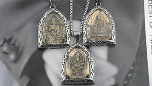Detailed close-up of religious titanium steel pendants featuring Ganesha and Buddha motifs