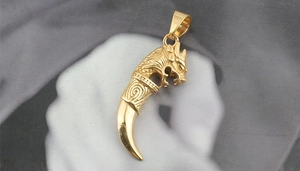Macro detail of golden dragon head pendant with smooth wolf tooth shape for men