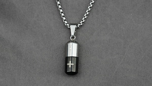 Macro d'un collier pendentif capsule argent et noir avec un motif de croix minimaliste