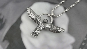 Macro detail of vintage eagle pendant with textured feathers and rustic finish on box chain