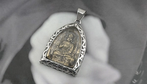 Detail of titanium steel Buddhist pendant featuring Buddha Shakyamuni in gold relief
