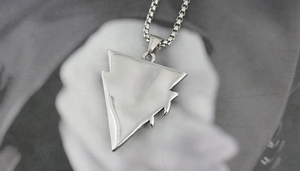 Polished silver arrow-shaped pendant and box chain on a minimalist portrait background