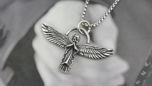 Detail of vintage angel pendant necklace with oxidized wings on a silver box chain