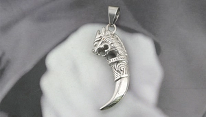 Detailed view of vintage silver dragon head pendant with a sharp wolf tooth design