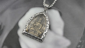 Macro detail of Buddhist pendant with carved Buddha and stainless steel chain link