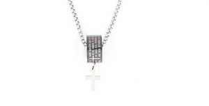 Macro shot of silver box chain with a black cylinder pendant engraved with Spanish prayer