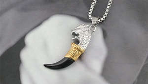 Detail of a retro wolf tooth pendant necklace in silver, gold and black with box chain