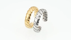 Detail of gold and silver twisted rope rings with a polished metallic finish and C-shape